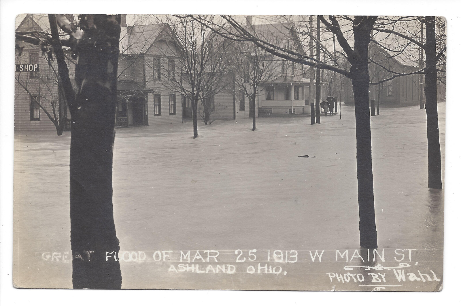 Historical photographic postcard of floodwater around buildings and trees on West Main Street, captioned March 25, 1913.