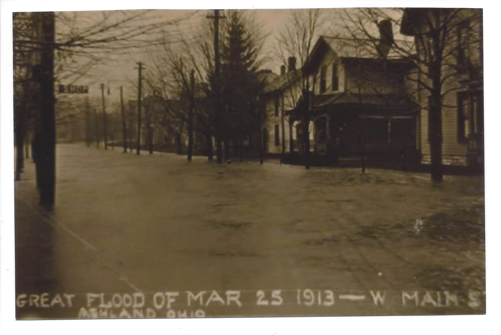 A second historical West Main Street flood view with buildings, trees and floodwater, captioned March 25, 1913.